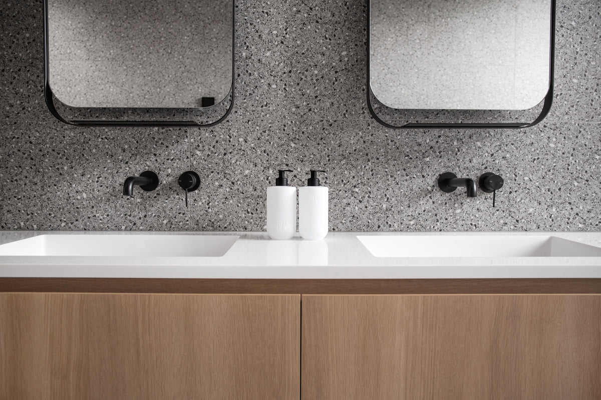 Twin-basin vanity with timber drawers, terrazzo wall and Smith & Co. bottles between the basins