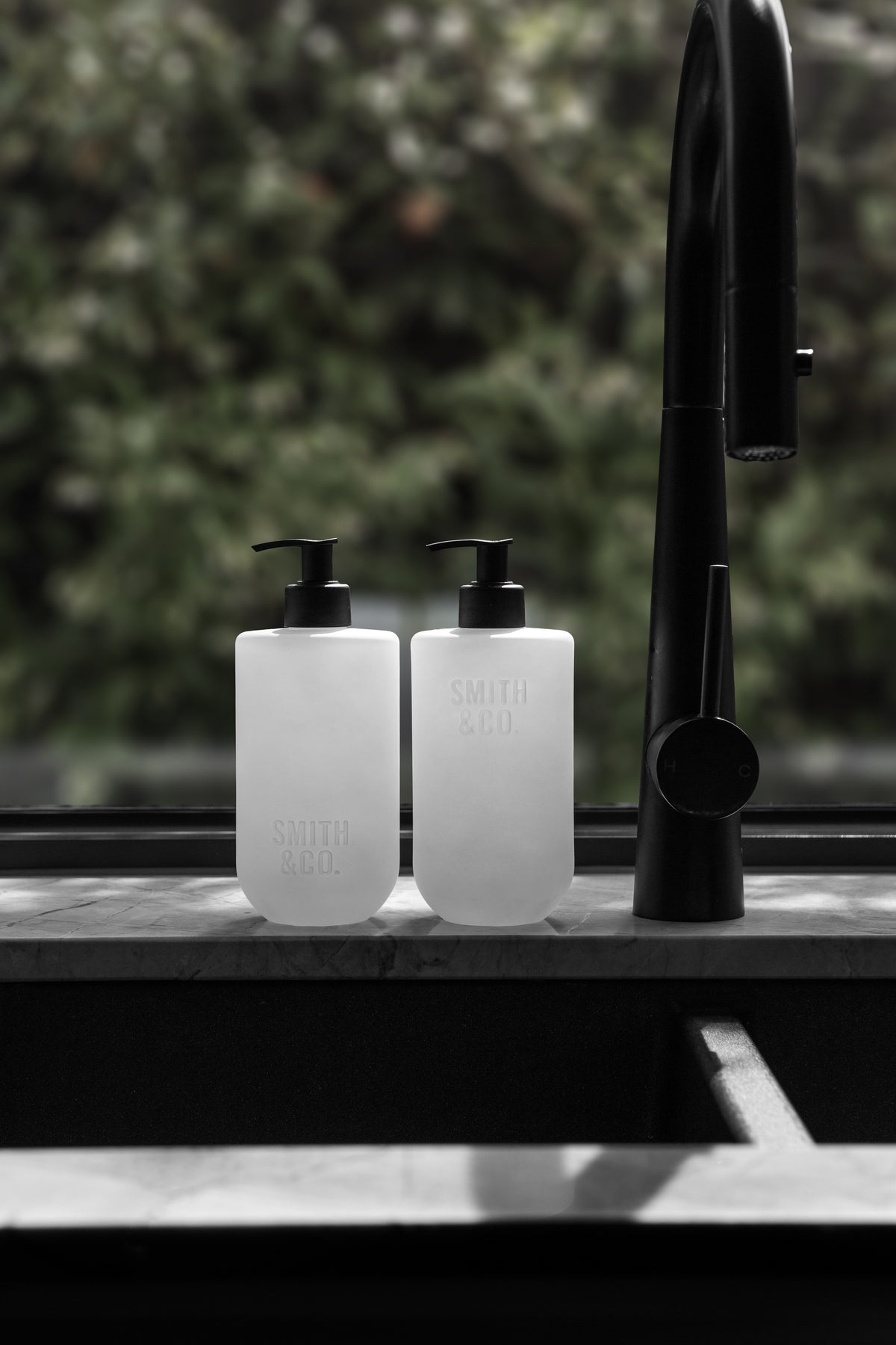 Smith and Co bottles beside a black tap at a dark kitchen sink