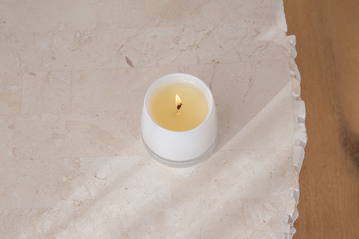 Top view of a lit Therapy candle on a pale surface
