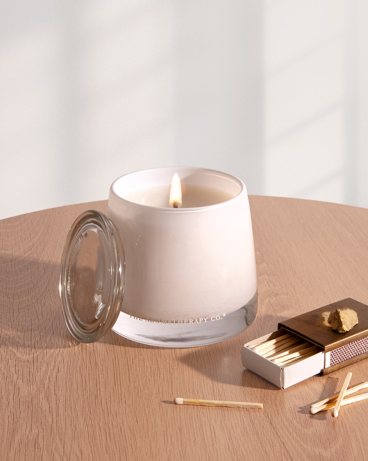 Lit Therapy candle on a timber tray beside a wick trimmer