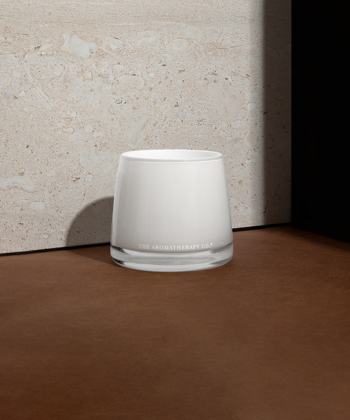 Therapy candle on a dark timber surface against a textured wall