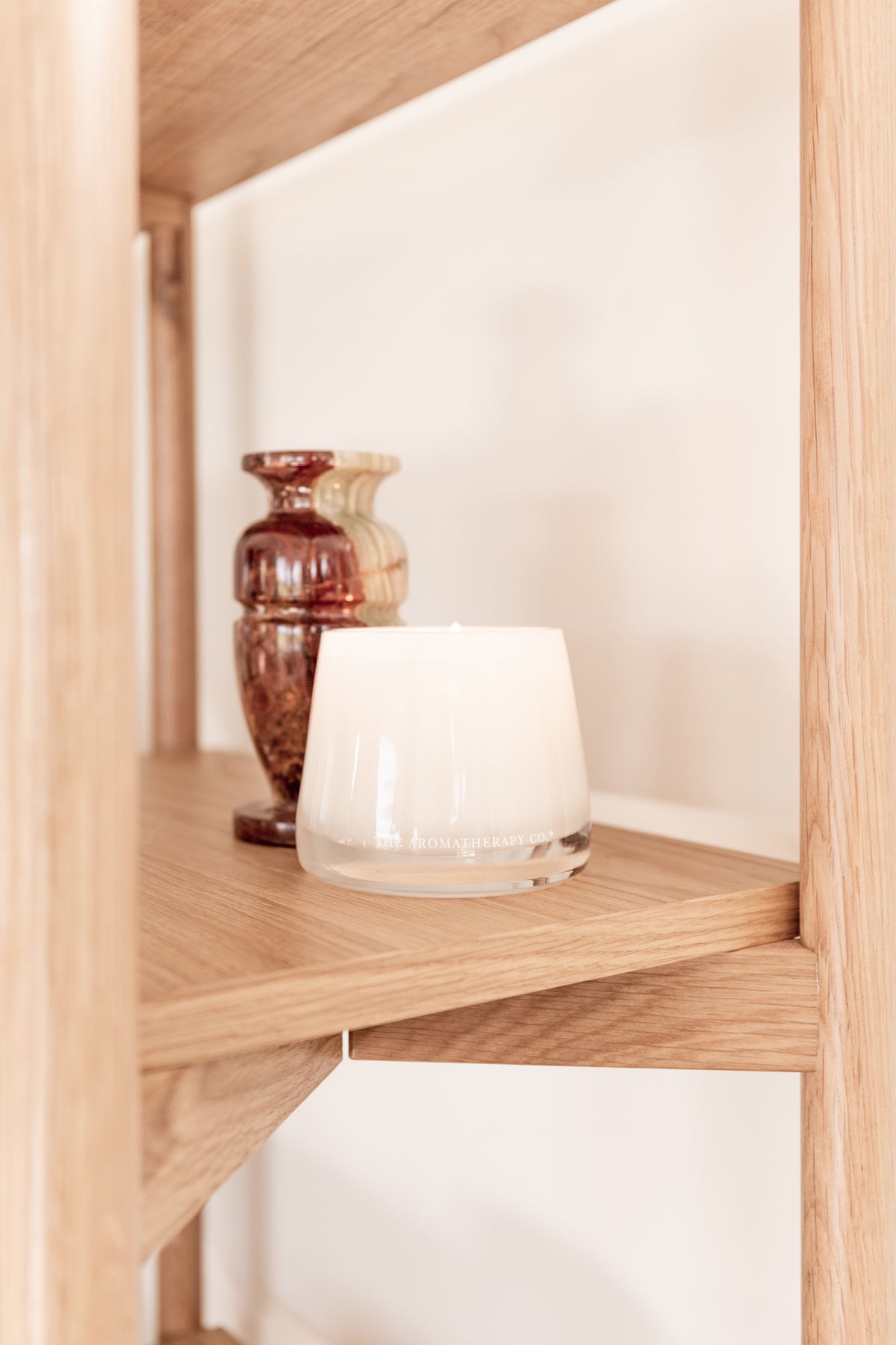 Therapy candle beside a patterned vase on an oak shelf