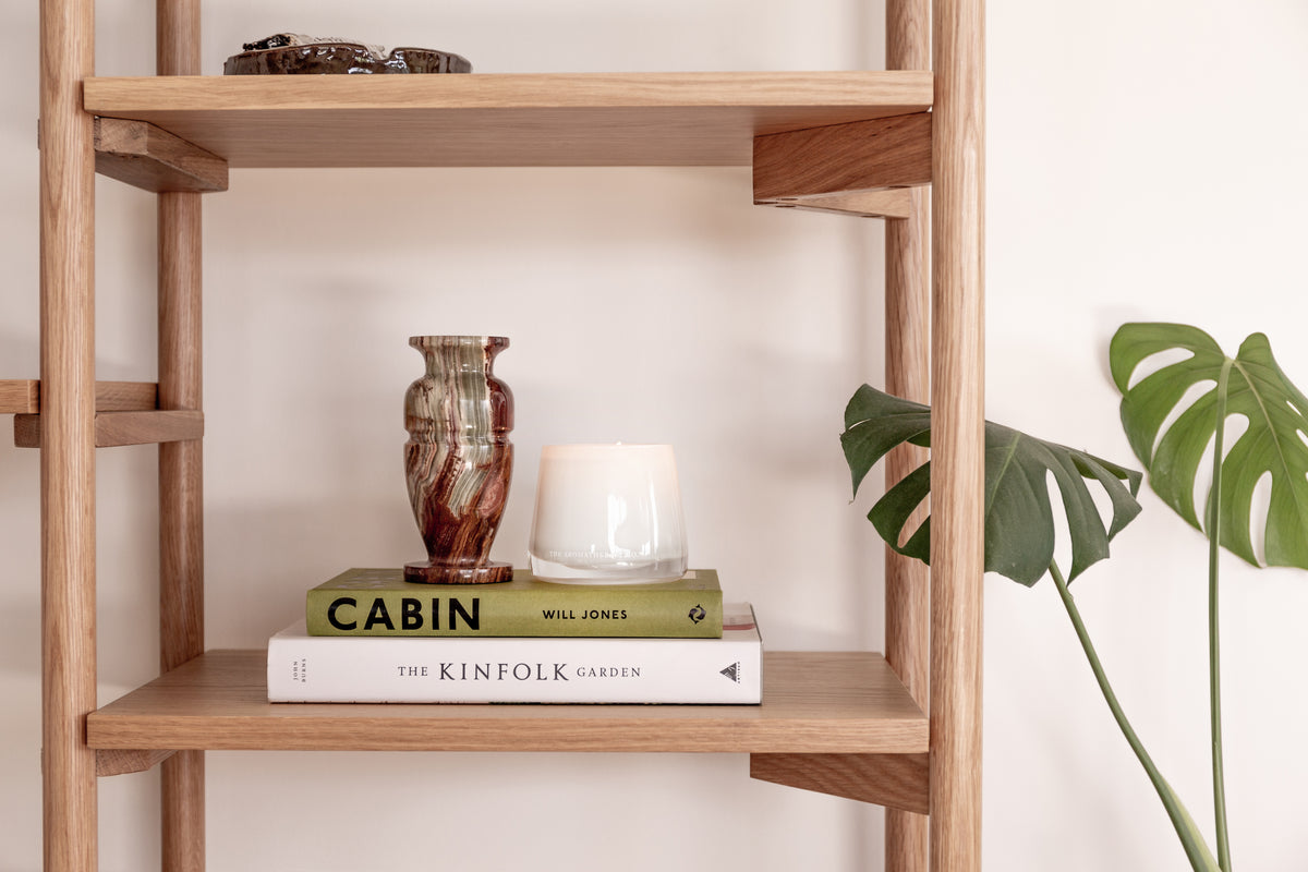 Therapy candle on a timber shelf with books and a plant