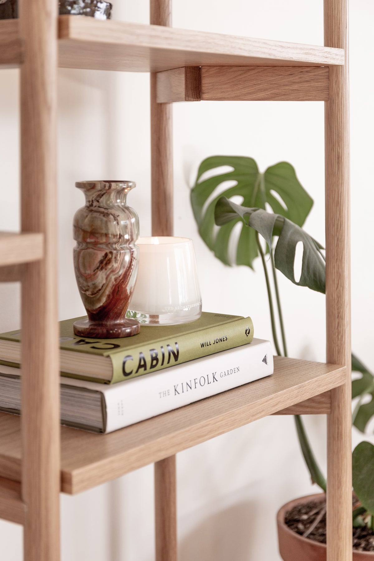 Oak shelving styled with a Therapy candle, books, a vase and plants