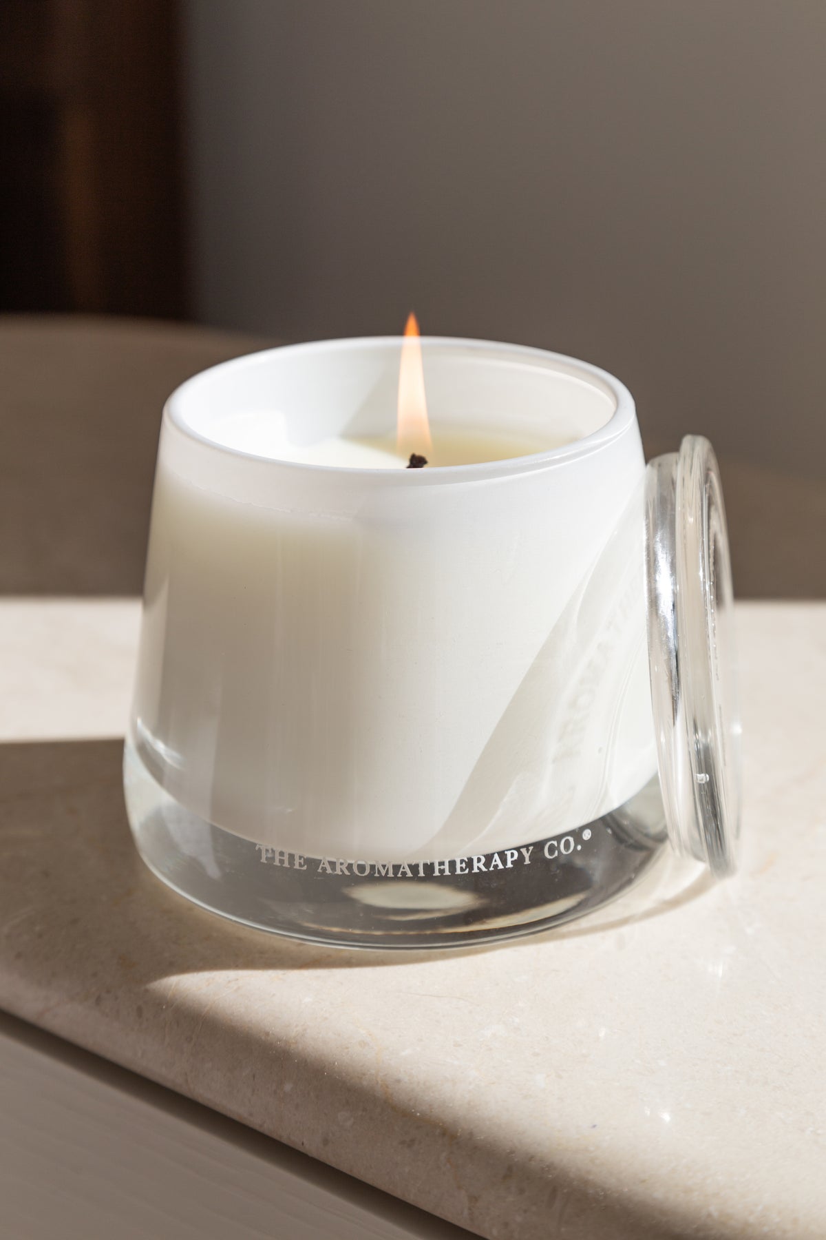 Lit Therapy candle in frosted glass on a pale surface