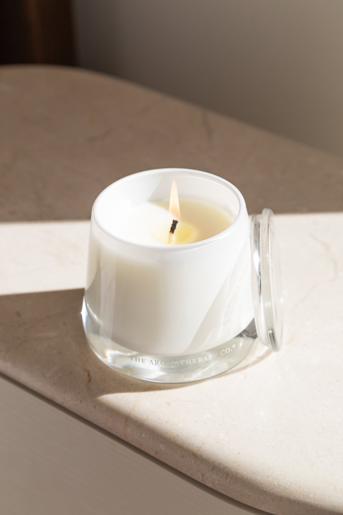 Close view of a lit Therapy candle on a curved pale sideboard