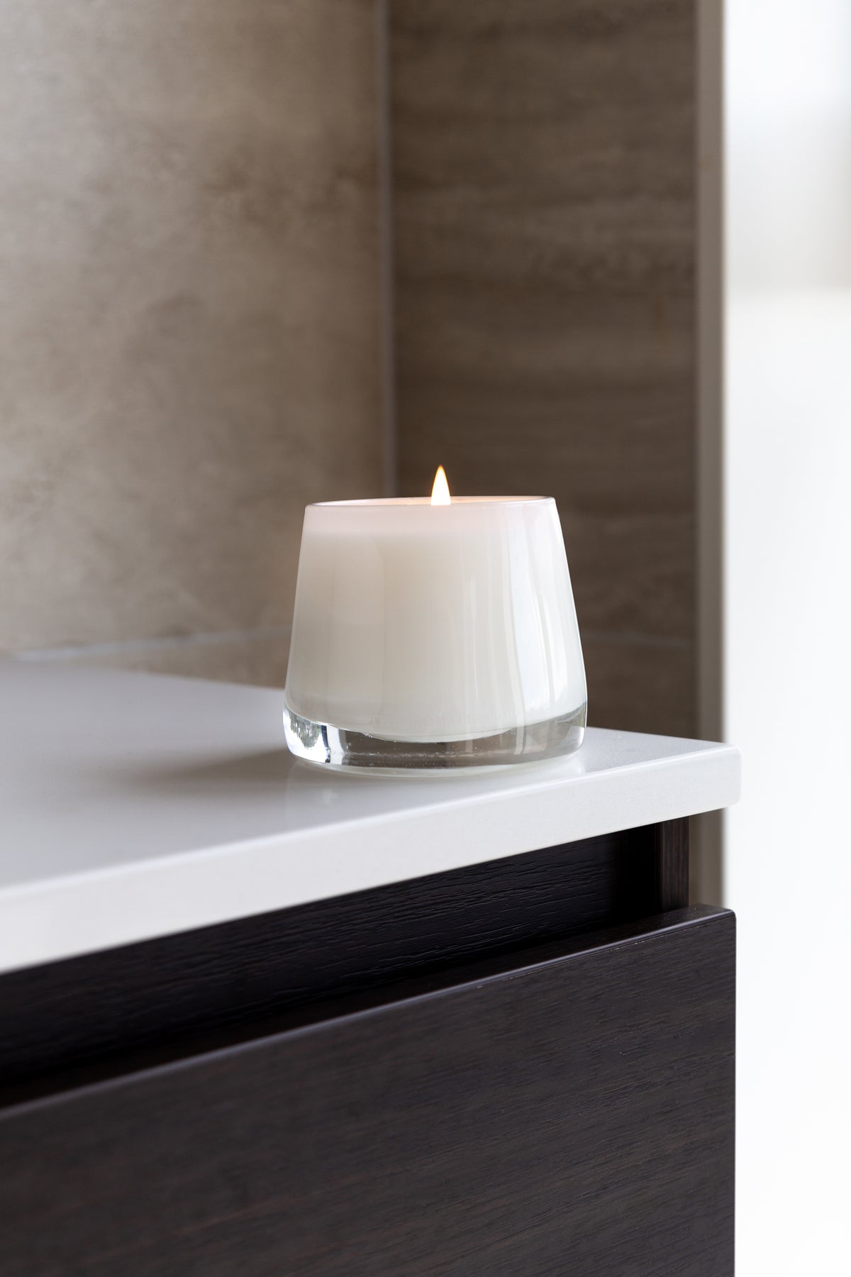 Therapy candle on a white vanity above dark timber drawers