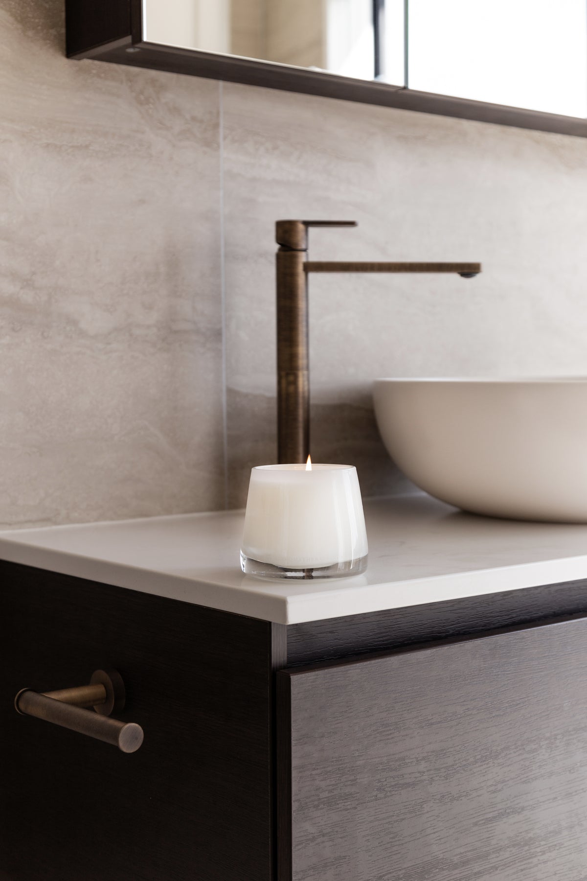 Therapy candle on a white bathroom vanity with a black tap