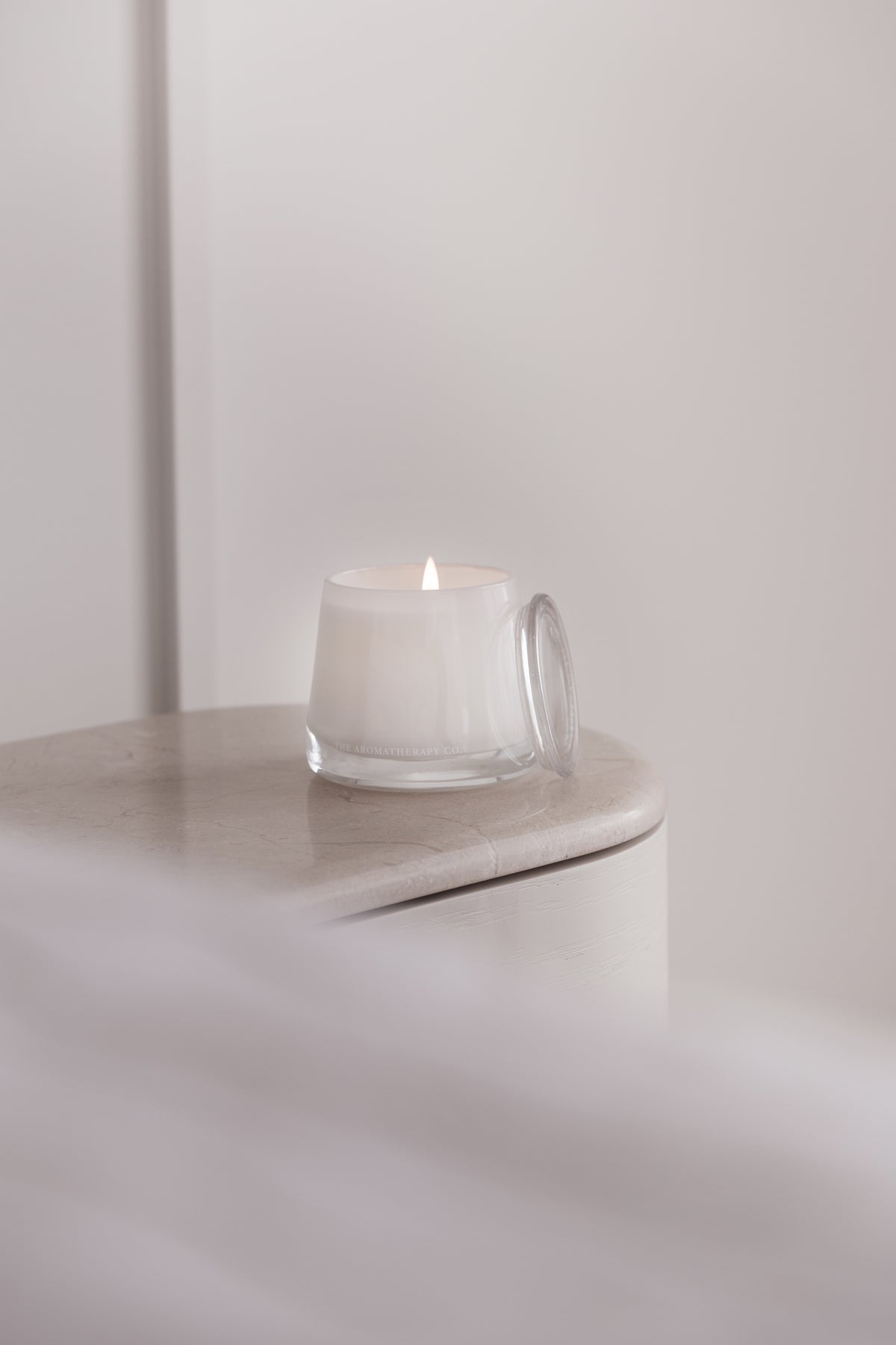 Therapy candle on a pale side table beside a bed