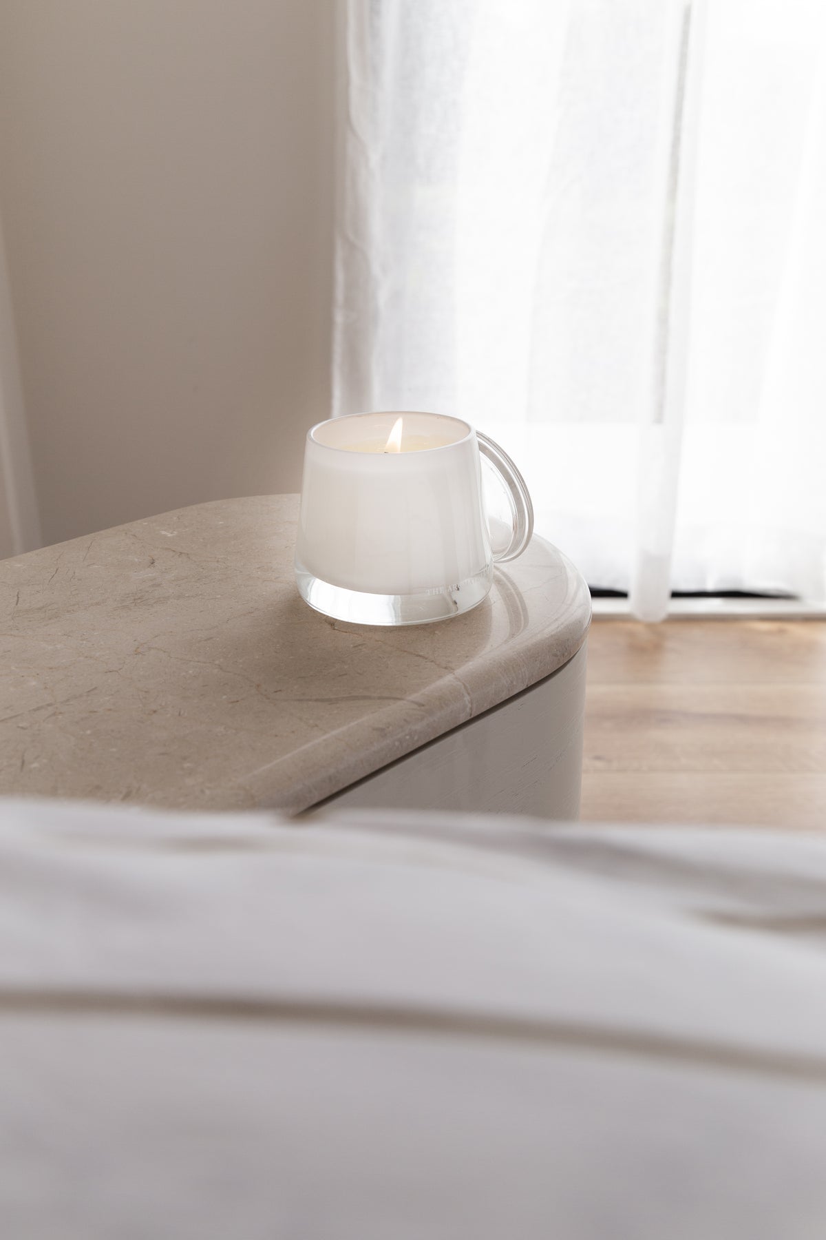 Therapy candle on a curved bedside table in a neutral bedroom
