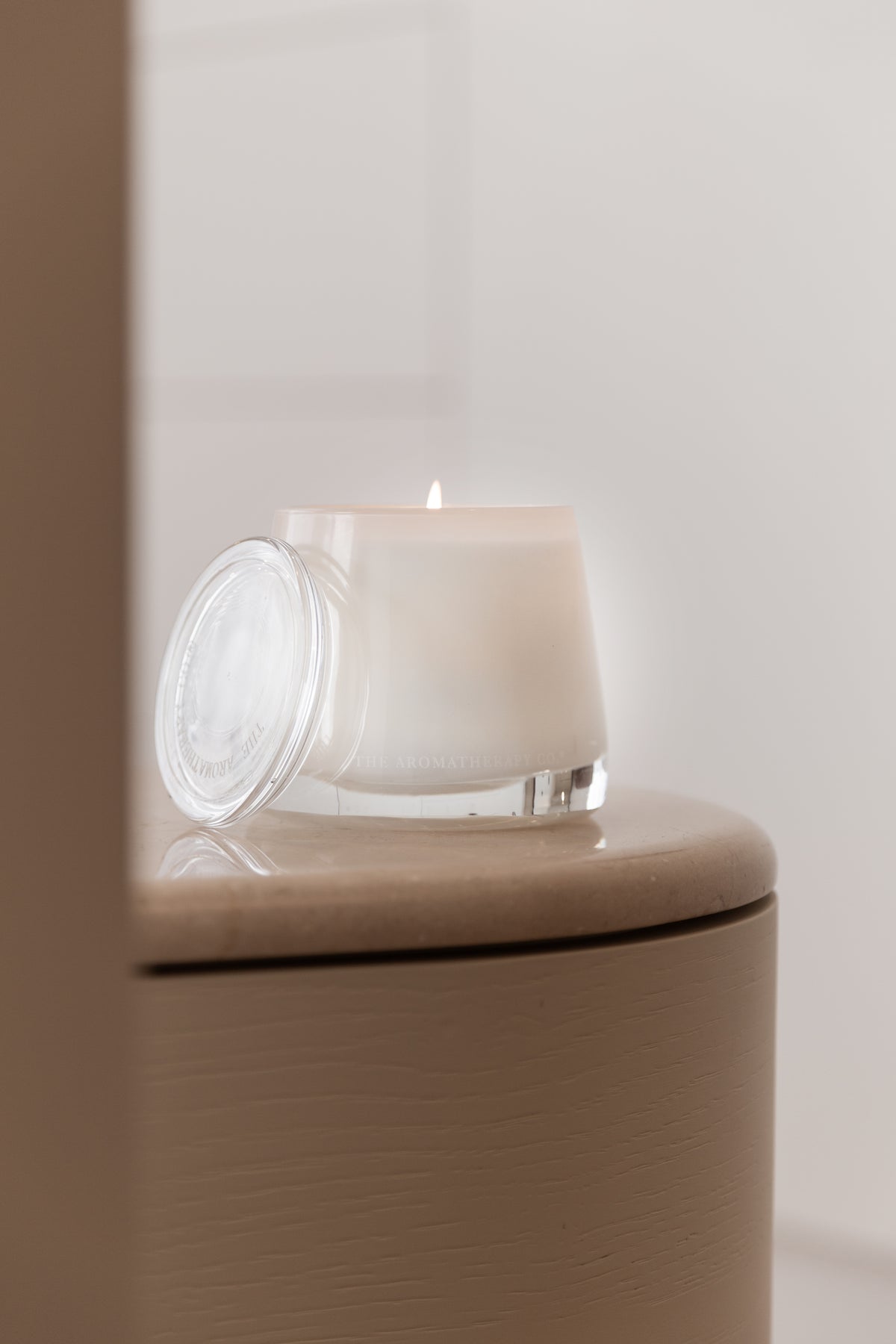 Therapy candle on the edge of a curved taupe side table