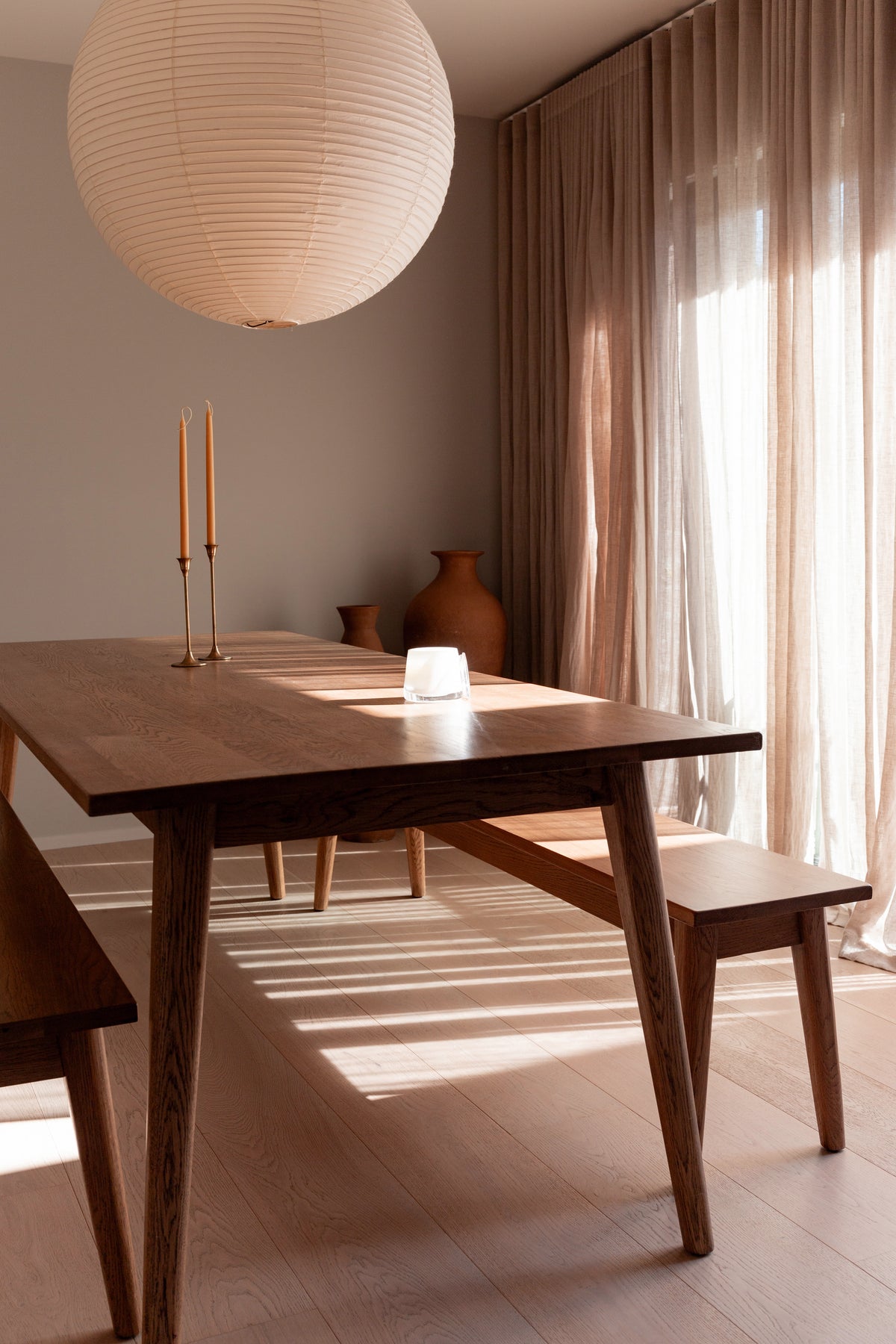 Therapy candle on a dining table beneath a paper pendant light