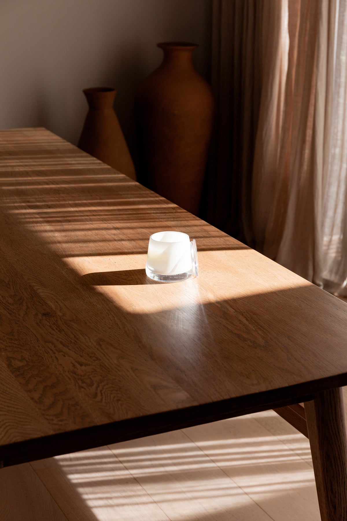 Therapy candle on a long timber table in soft window light
