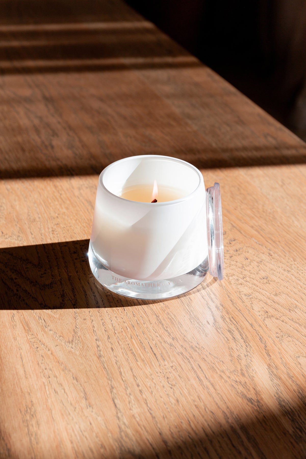 Close view of a lit Therapy candle on sunlit timber