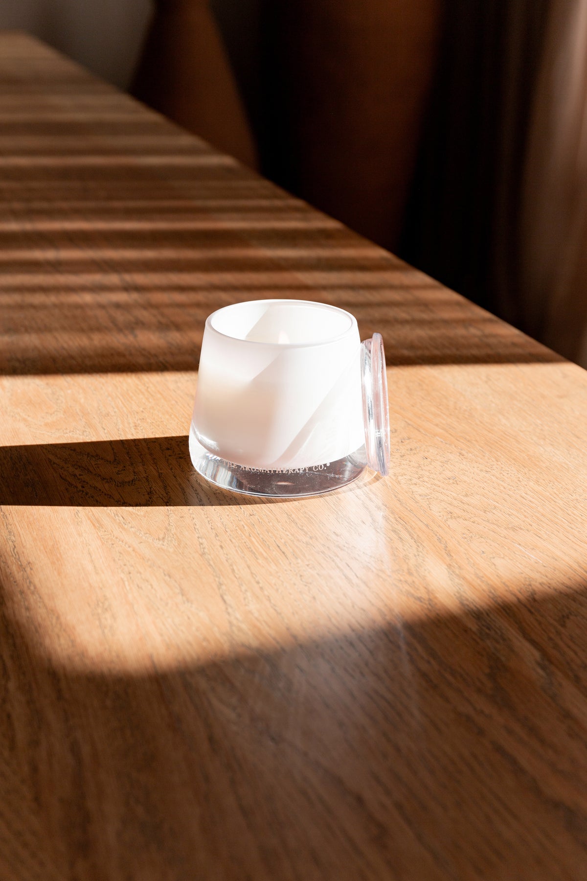 Therapy candle catching sunlight on a dark timber surface