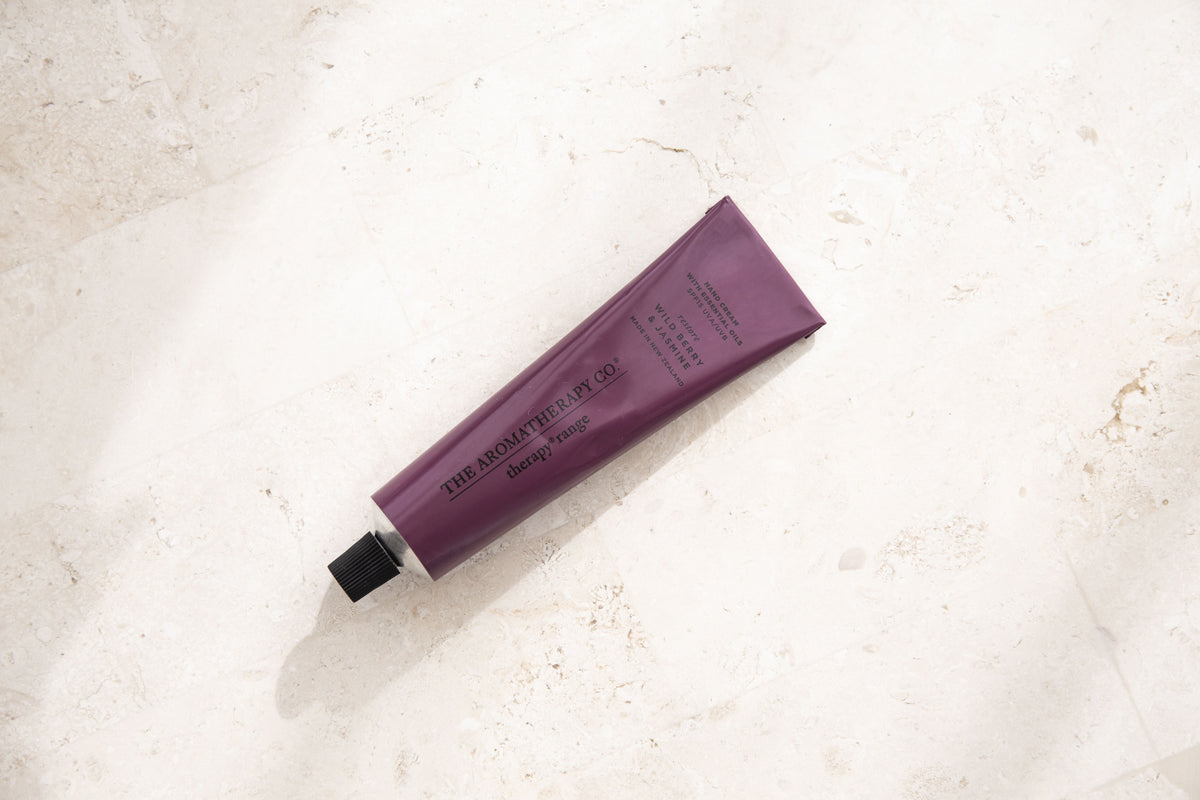 Plum hand cream tube lying on its own on a sunlit pale stone surface
