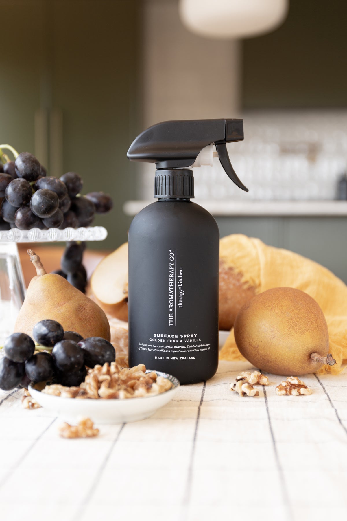Black surface spray on a white table with pears, dark grapes and walnuts arranged around it