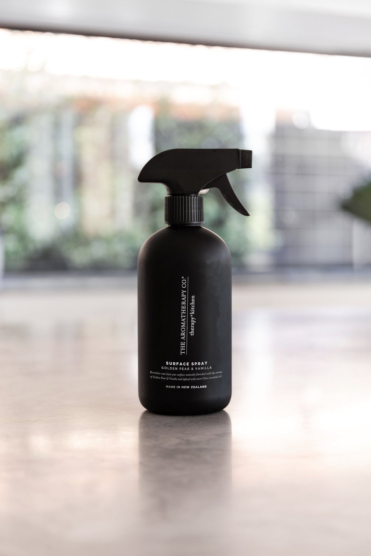 Black surface spray bottle on a polished stone bench with a bright window behind