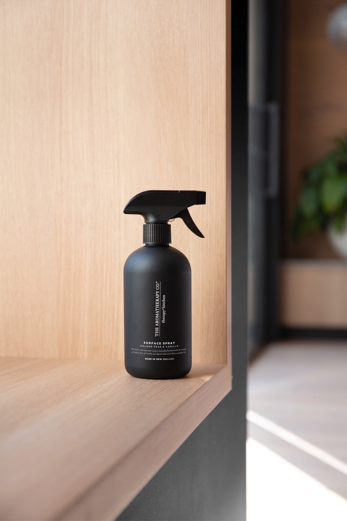 Black surface spray bottle on a timber window ledge in afternoon sun