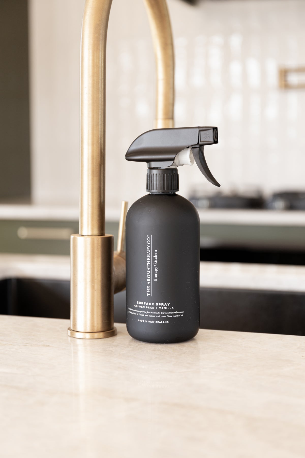 Black surface spray beside a brass tap on a stone benchtop