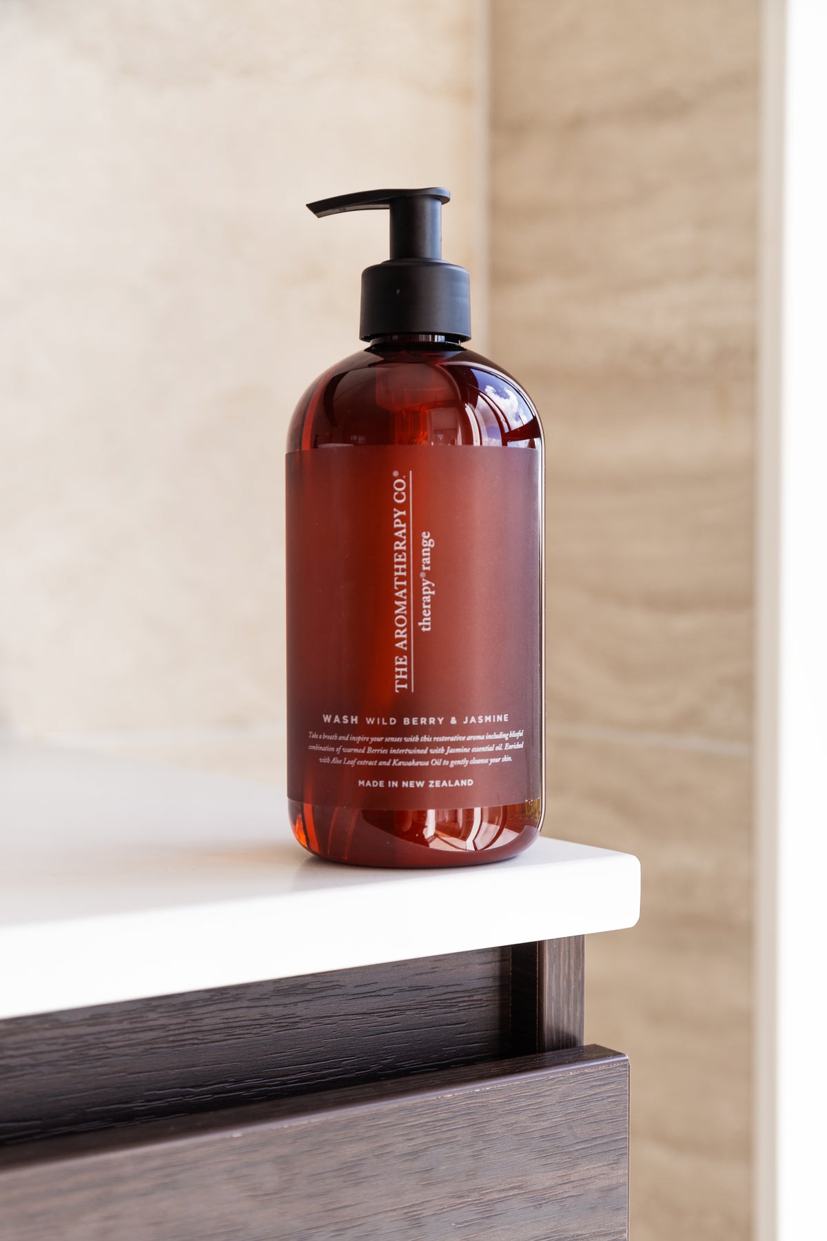 A single amber Therapy pump bottle on a white ledge above dark timber cabinetry