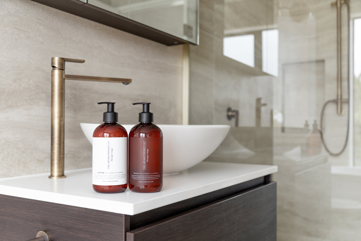 White vessel basin on a dark timber vanity with two amber pump bottles alongside