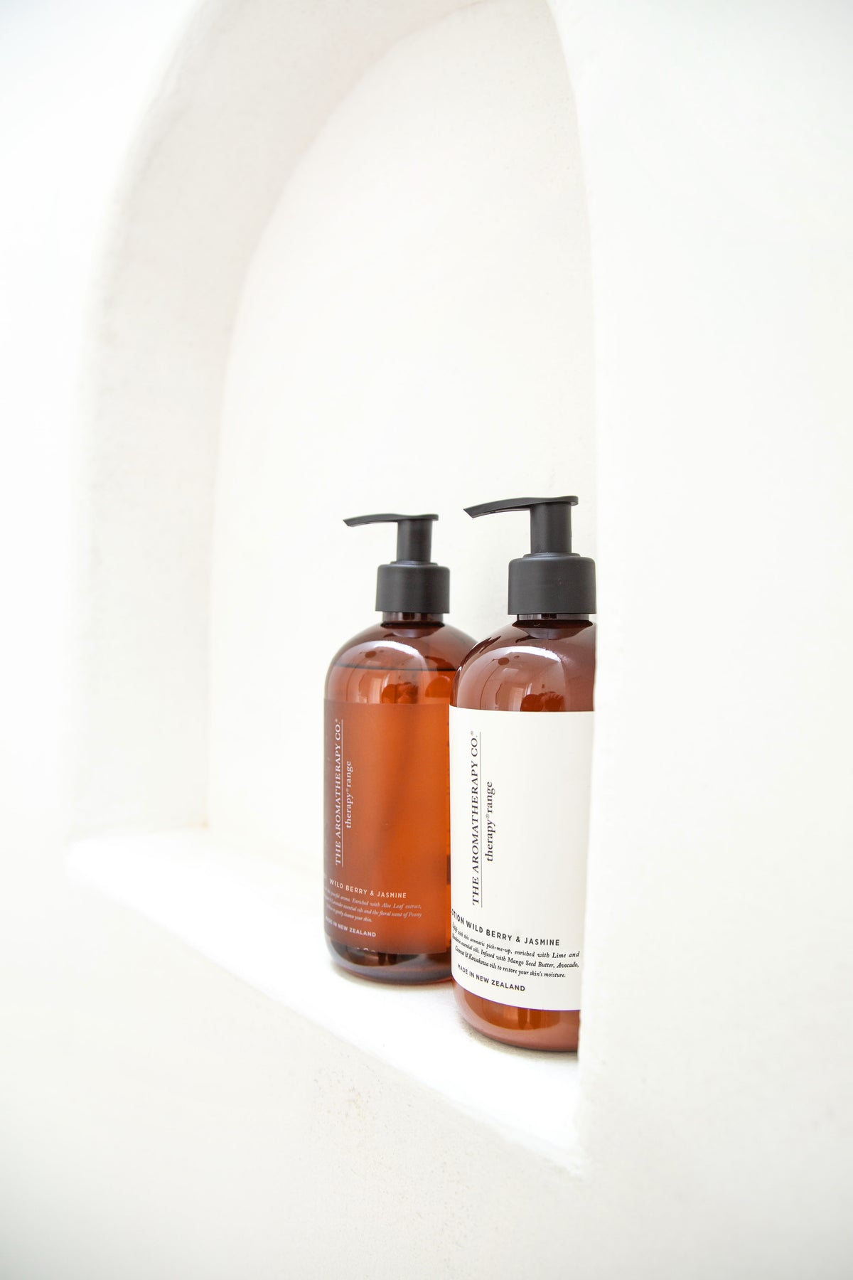 Two amber pump bottles set into a curved white arched niche