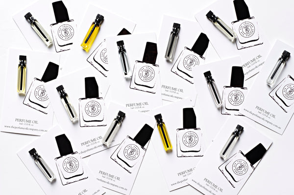 Overhead spread of perfume oil sample vials and roll-ons on scent cards