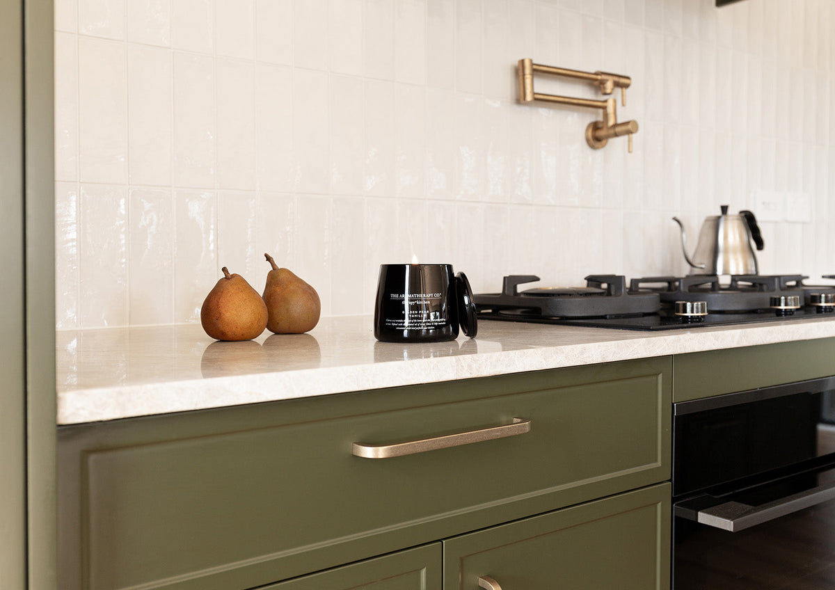 Olive green kitchen with two pears, the Therapy Kitchen candle and a kettle on the bench
