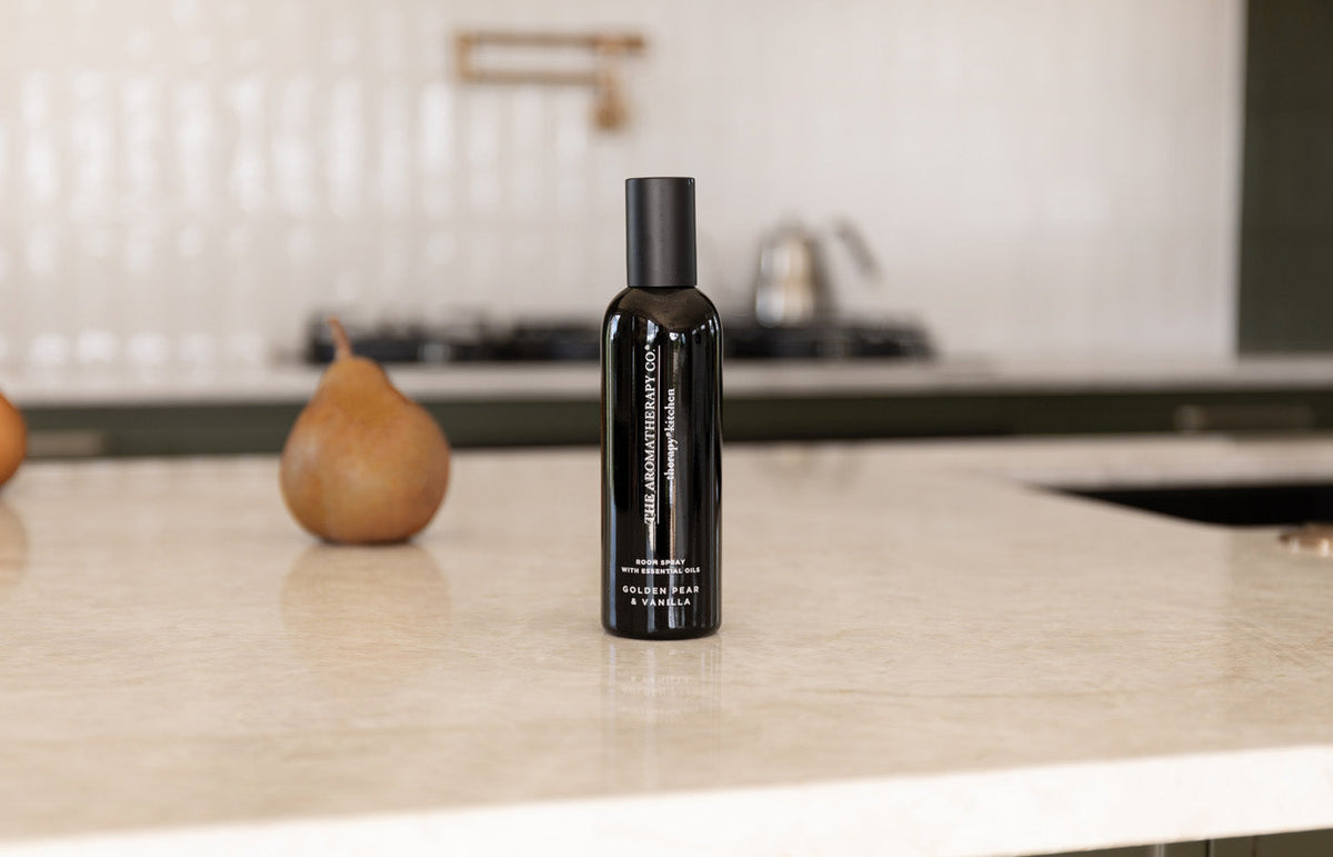 Black room spray on a stone kitchen island with a single pear, landscape view