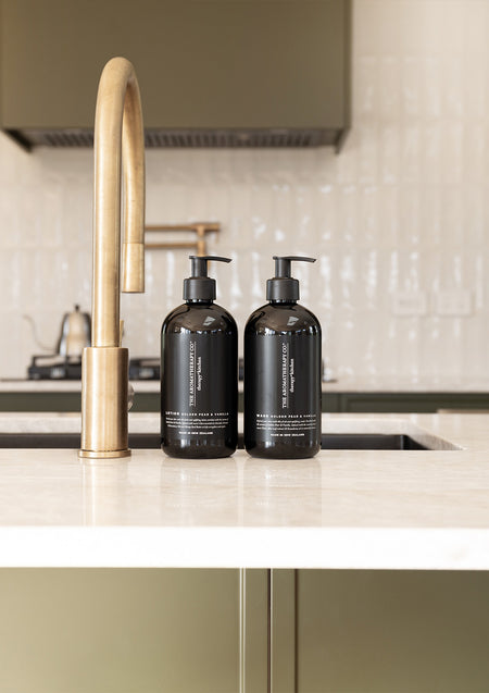 Black Therapy Kitchen hand wash and lotion bottles by a kitchen sink with a brass tap