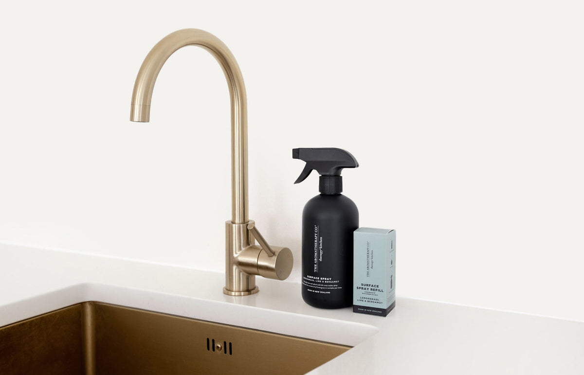 Black Therapy Kitchen surface spray and its refill box by a brass tap and sink