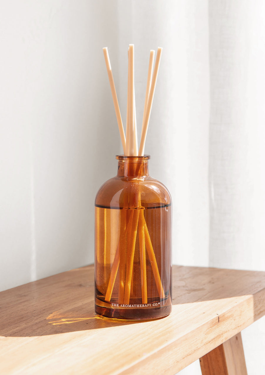 Therapy amber reed diffuser on a honey-toned timber bench against a white wall