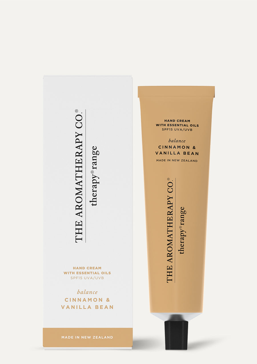 Cinnamon & Vanilla Bean hand cream tube beside its white and caramel box on a pale background
