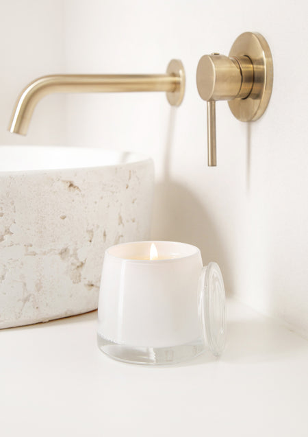 Therapy candle on a stone basin beside a brass tap