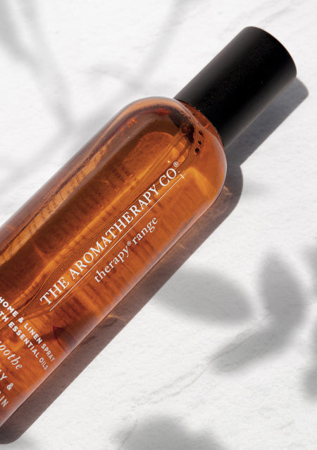 Close crop of the amber Therapy spray bottle on white with leafy shadows