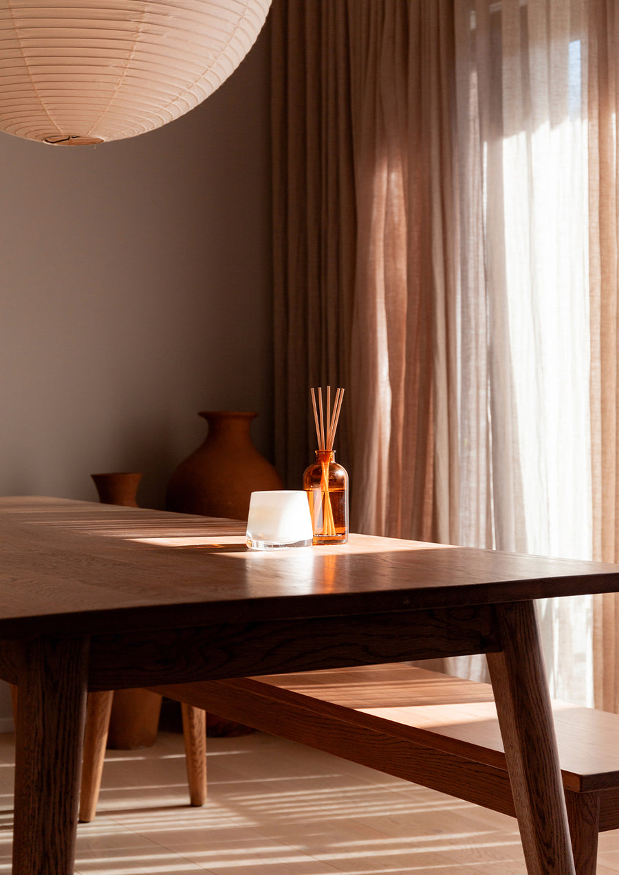 Therapy reed diffuser on a dark timber dining table in a softly lit room