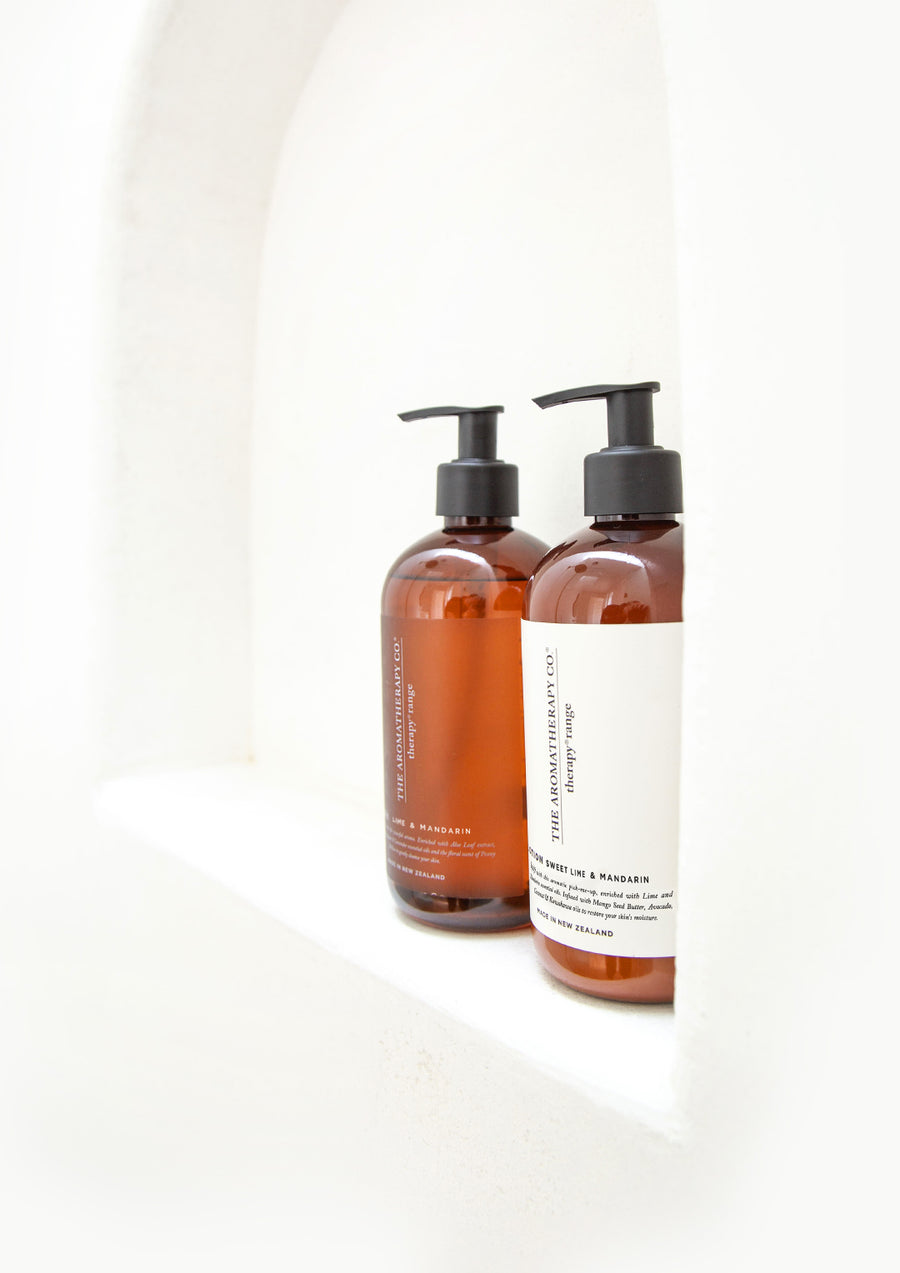 Close view of two amber Therapy pump bottles in an arched white shower niche