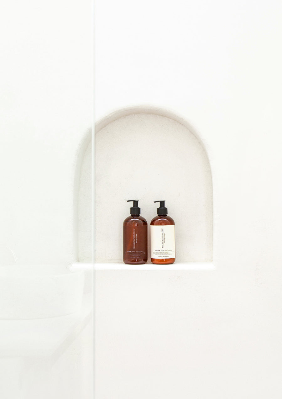 Two Therapy pump bottles in an arched niche in a white rendered shower wall