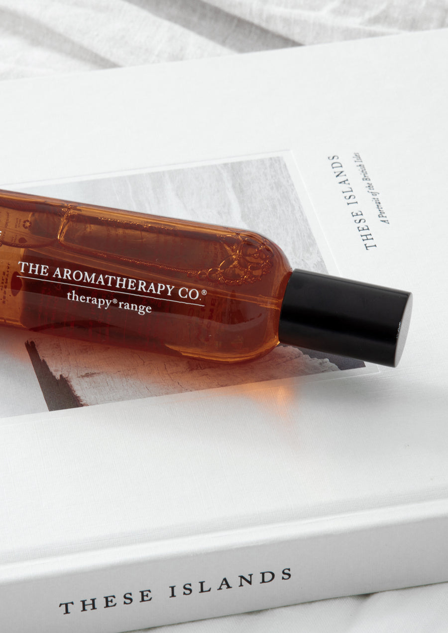 Amber room spray bottle lying on an open coffee table book, seen from above