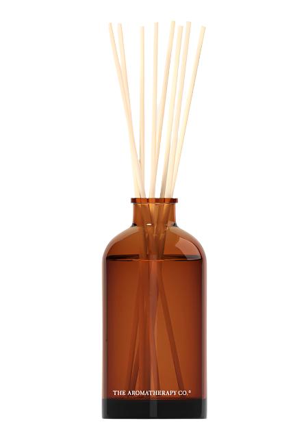 Therapy amber glass reed diffuser with pale reeds on a plain background