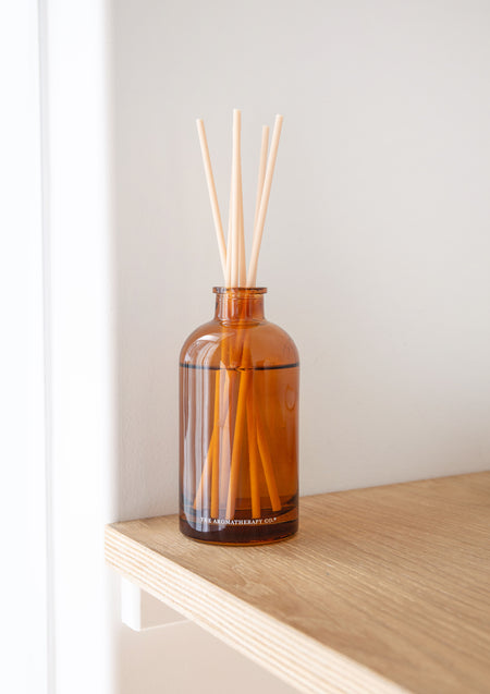 Therapy amber diffuser on the edge of a pale timber shelf
