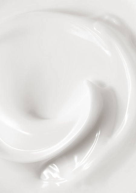Close view of a thick white body lotion swirl, smooth and glossy