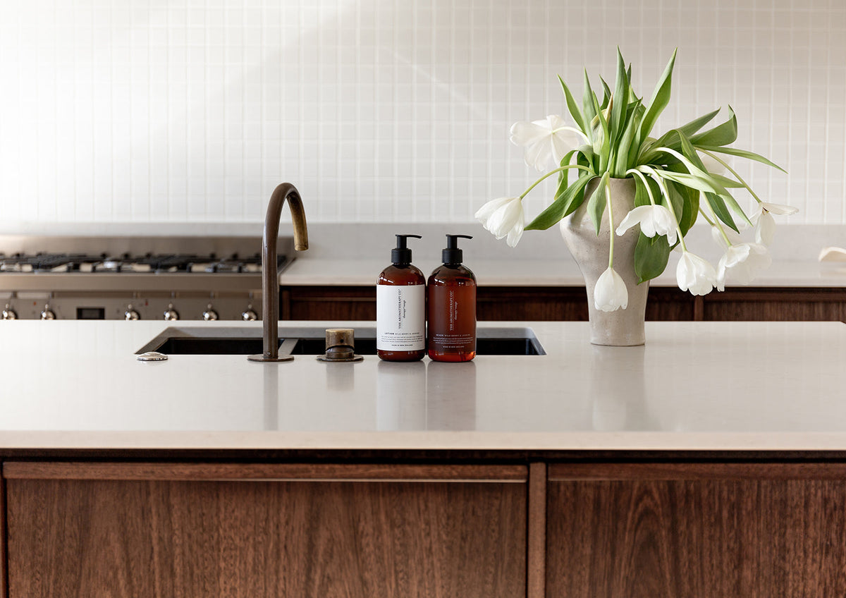Dark timber kitchen with a tiled splashback, Therapy bottles and tulips beside the sink