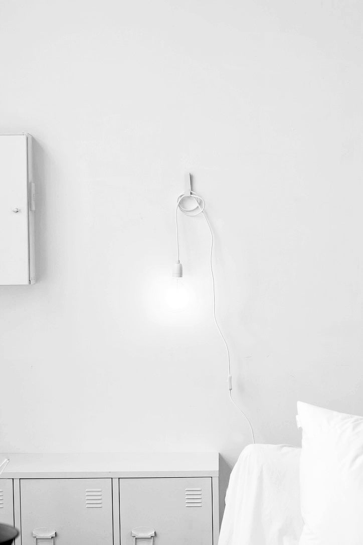 Plug-in pendant with white cord and clear bulb in a minimal white room