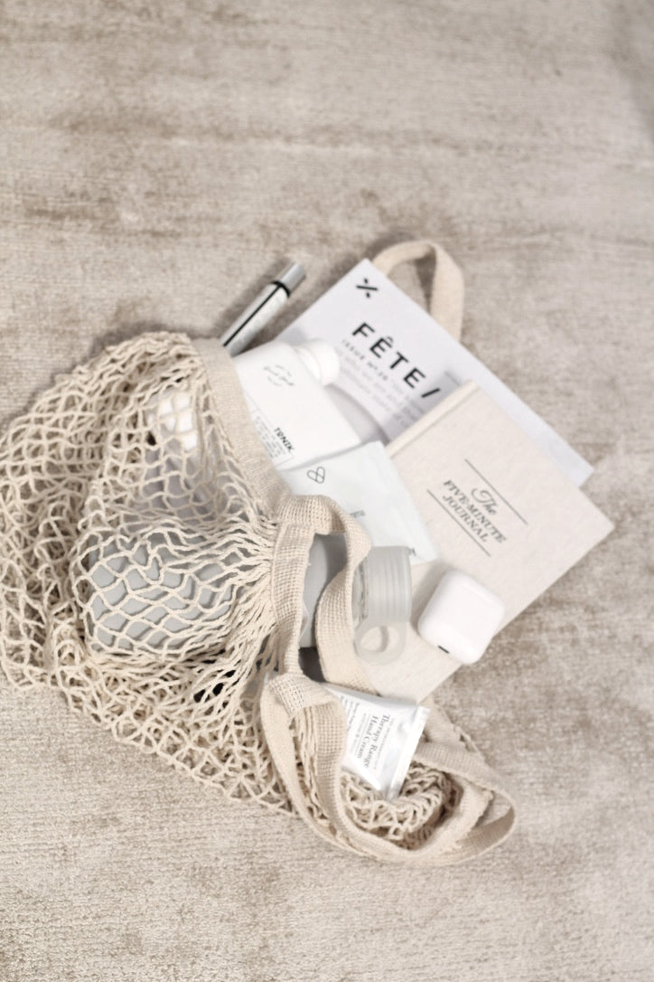 Crocheted bag holding a journal and cards on a stone surface
