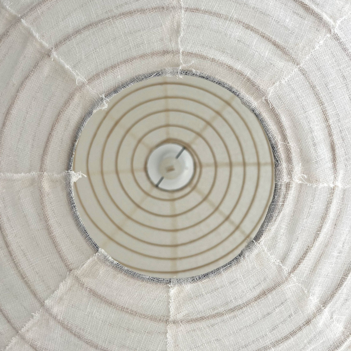 Round pendant shade over a neutral living room with sheer curtains at the windows