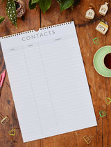 A desk with a Write To Me 2024 FAMILY CHAOS PLANNER and a cup of coffee next to it, amidst the chaos of family life.
