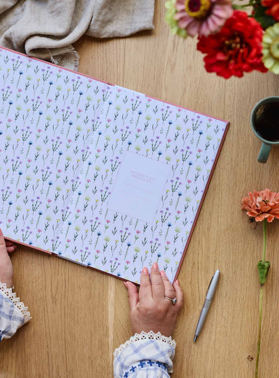 Photo journal open flat showing its floral endpapers, with flowers alongside