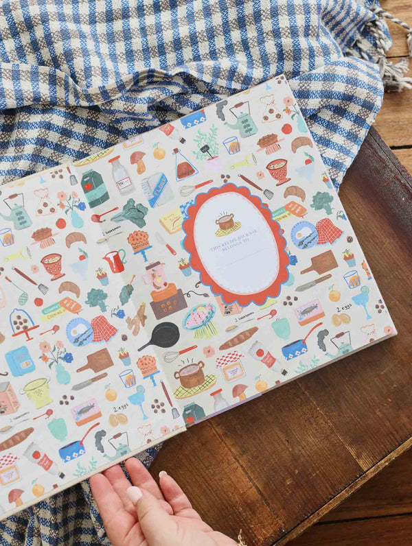 Hands opening the recipe journal to its colourful illustrated endpapers